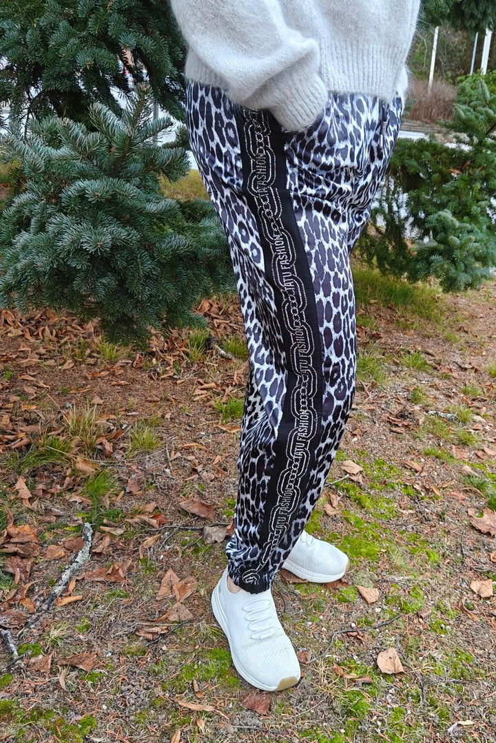 Satiinihousut leopardikuosilla, kimallekoristein, rento istuvuus ja ohut materiaali.